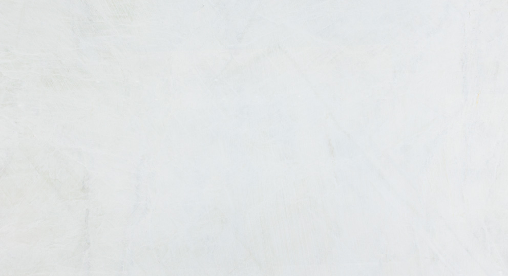 Large polished slab of snow white onyx marble with subtle gray veining displayed in a well-lit showroom environment